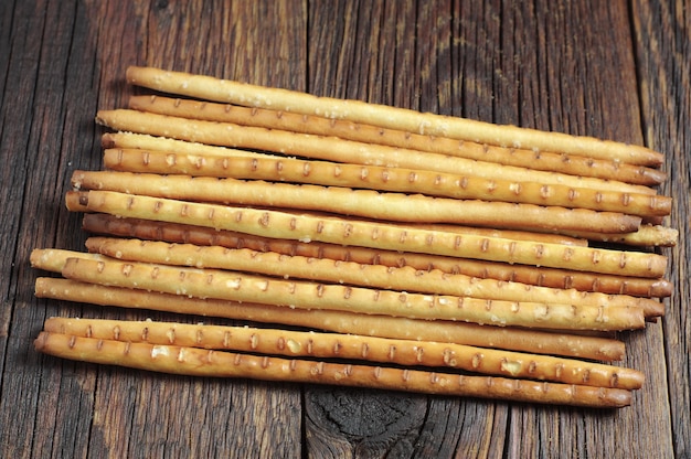 Heap salty breadsticks on dark wooden table