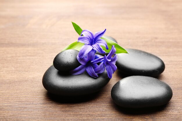 Photo heap of spa hot stones and flowers on wooden background