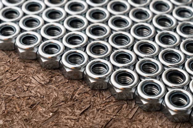 Photo heap of stainless screw-nuts on wooden background.