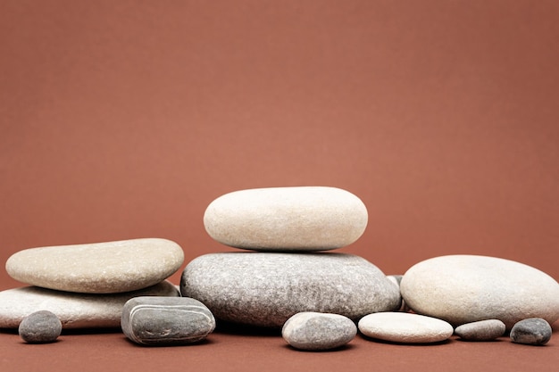 Heap of stones pebbles on brown background podium for product presentation copy space