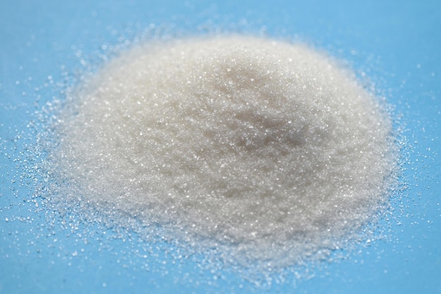 Heap of sugar on blue background white sugar for food and sweets dessert candy heap of sweet sugar crystalline granulated