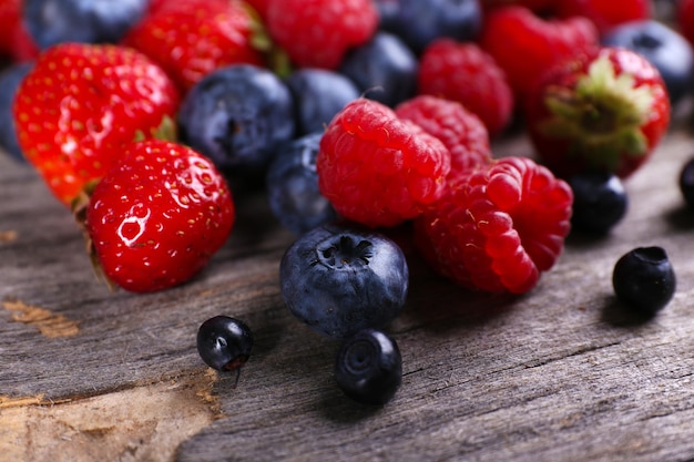 Heap of sweet tasty berries on wooden table close up