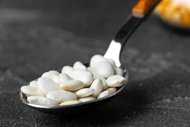 Heap of uncooked beans in a spoon on kitchen table