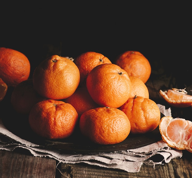 Heap of unpeeled round ripe orange mandarin on a gray linen napkin