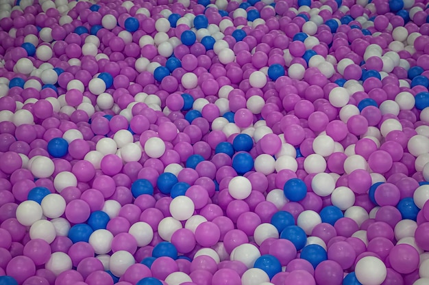 Куча белых, синих и фиолетовых пластиковых шаров.