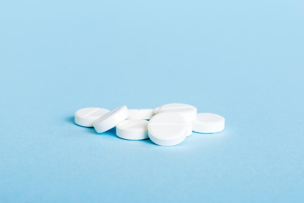 Heap of white pills on colored background Tablets scattered on a table Pile of red soft gelatin capsule Vitamins and dietary supplements concept