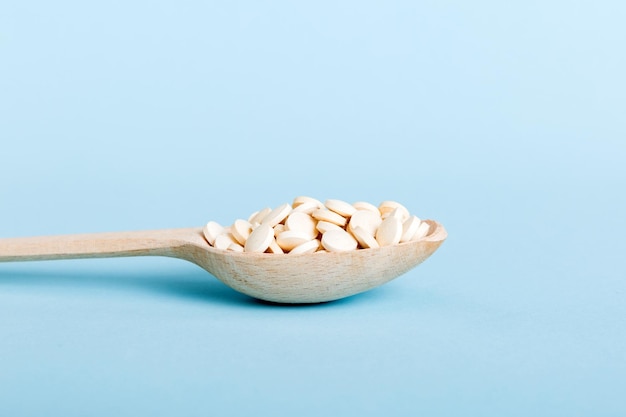 Heap of white pills on colored background Tablets scattered on a table Pile of red soft gelatin capsule Vitamins and dietary supplements concept