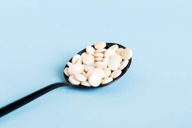 色付きの背景に白い錠剤の山テーブルに散らばっている錠剤赤いソフトゼラチンカプセルの山ビタミンと栄養補助食品の概念