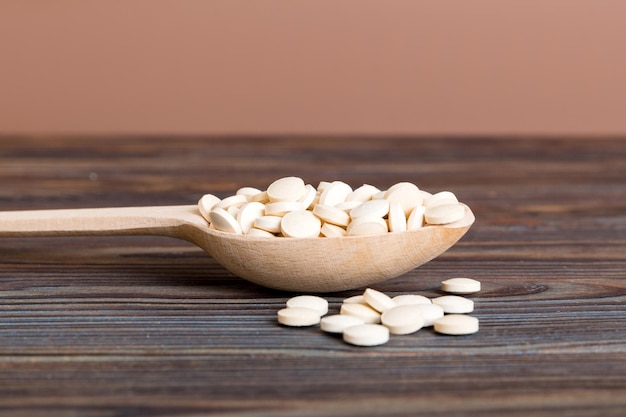 Heap of white pills on colored background Tablets scattered on a table Pile of red soft gelatin capsule Vitamins and dietary supplements concept