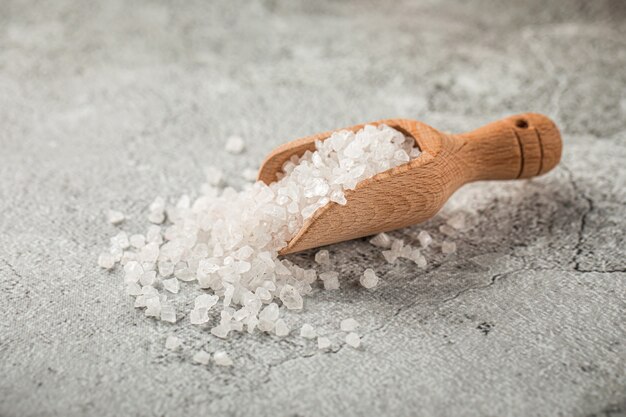 Heap of white salt in a wooden scoop