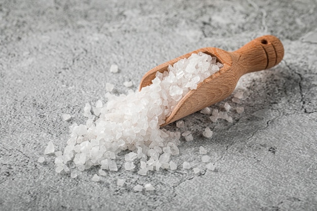 Heap of white salt in a wooden scoop