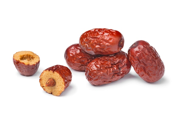 Heap of whole dried Chinese red dates and a halved one isolated on white background close up