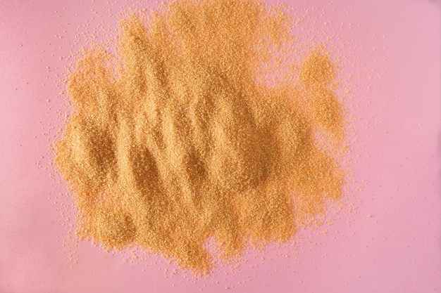 A heap with Dry brown sugar on pink background top view