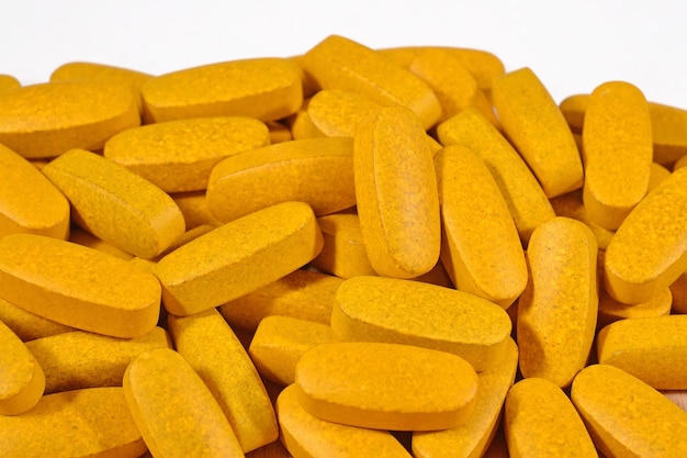 Heap of yellow pills on a white background