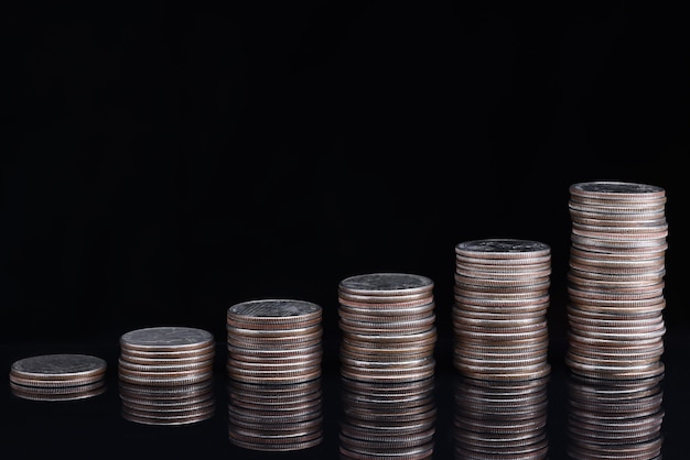 Heaps of coins standing in ascending order on black background