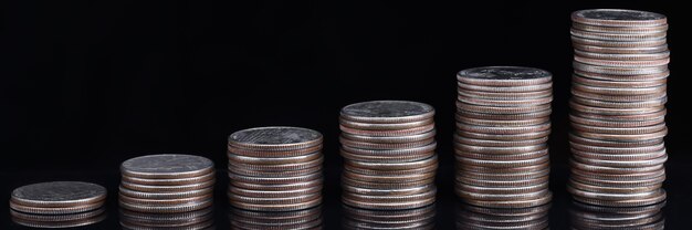 Heaps of coins standing in ascending order on black background