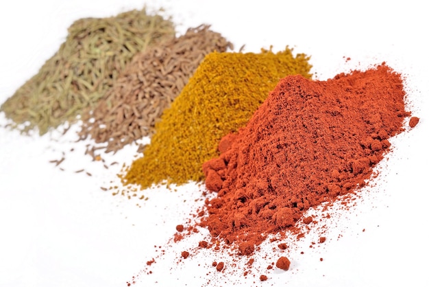 Heaps of different dry spices on a white background