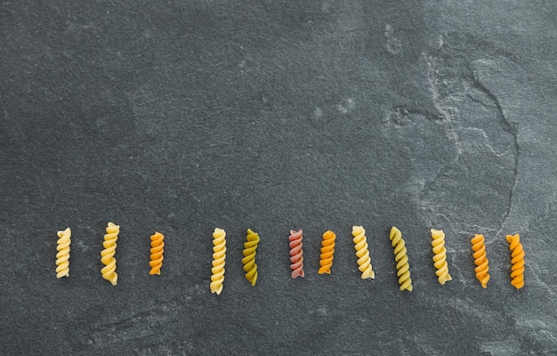 Heaps of pasta various colors farfalle pasta on dark background top view