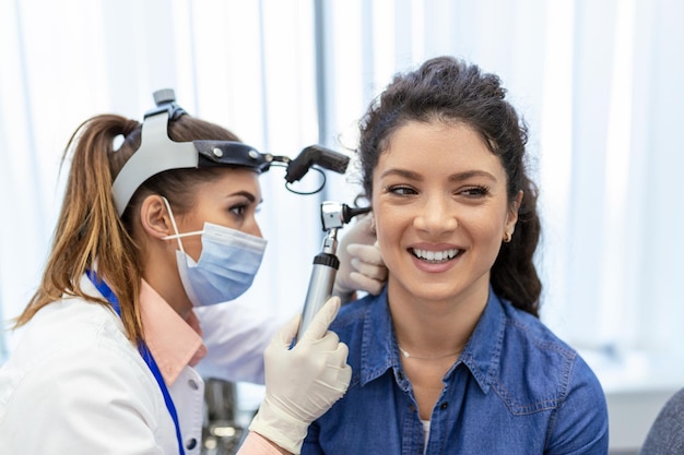 Hearing exam Otolaryngologist doctor checking woman's ear using otoscope or auriscope at medical clinic Otorhinolaryngologist pulling ear with hand and looking at it with otoscope closeup