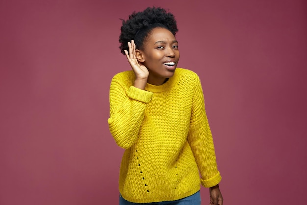 Hearing gesture curious african american young girl holding hand near ear trying to listen to