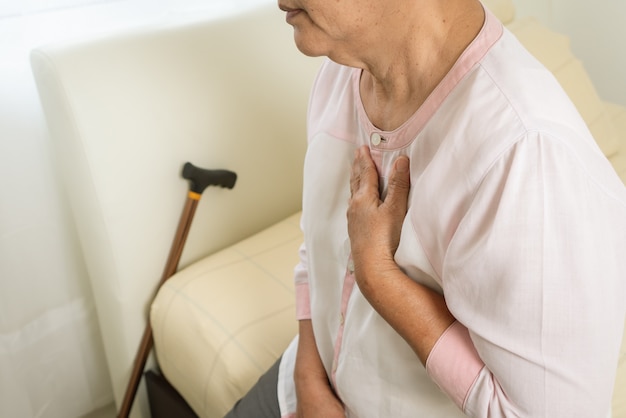 Heart attack old woman holding chest in bed room, healthcare problem of senior concept