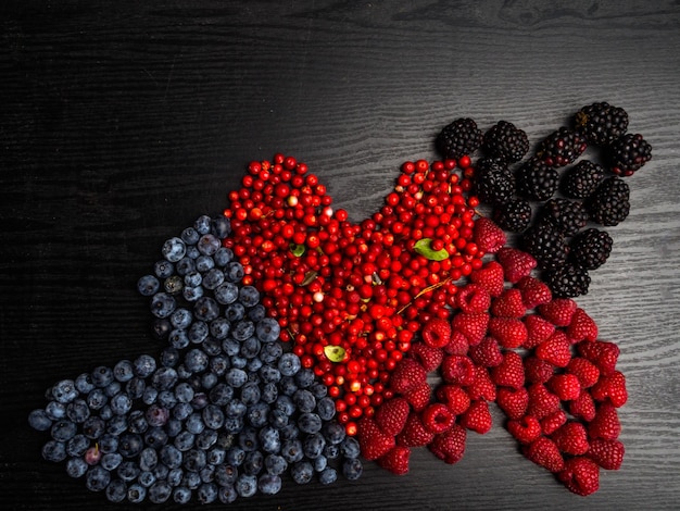 Heart of berries on a wooden background Red raspberries cranberry blueberry blackberry Tasty vitamin food