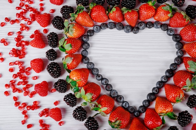 Heart of berries on wooden background