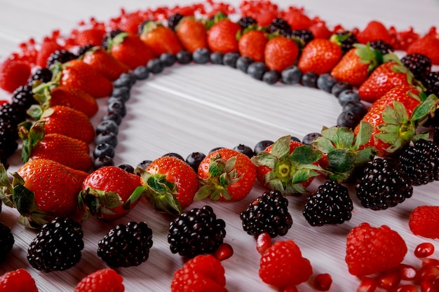 Heart of berries on wooden background