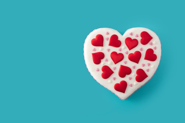 Heart cake for St. Valentine's Day,  decorated with sugar hearts on blue background