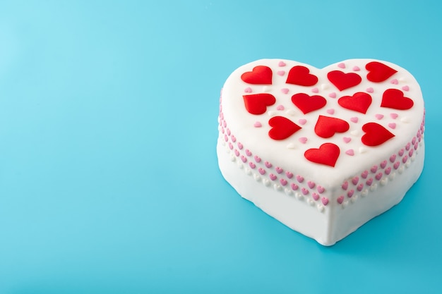 Torta cuore per san valentino, decorata con cuori di zucchero su sfondo blu