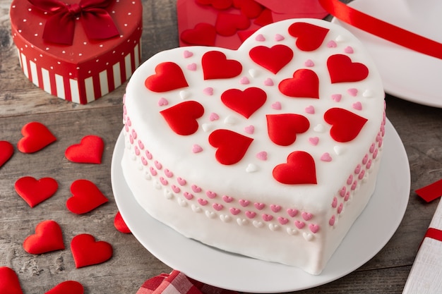 Torta di cuore per san valentino, decorata con cuori di zucchero sulla tavola di legno