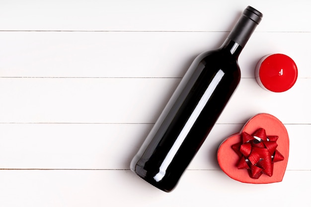 Heart, candle, wine bottle on white wooden surface. Valentine's day concept. Flat lay