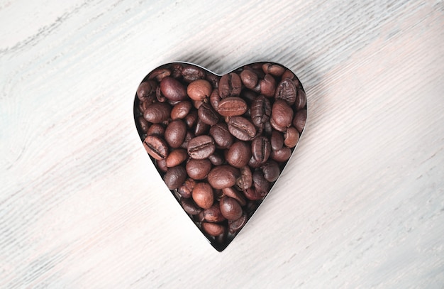 Heart of coffee beans on a light background. The view from the top.