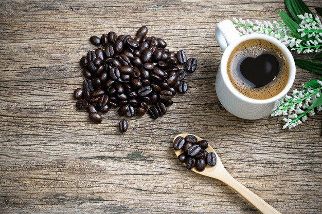 Heart coffee and coffee beans roasted in a sack on a wooden floor.