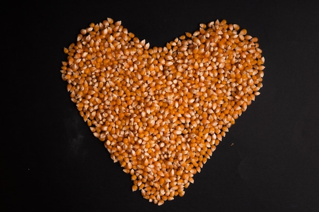 Heart of corn kernels on a black background top view