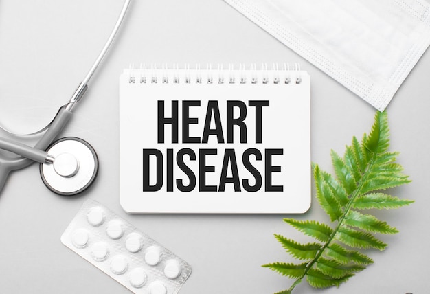 Heart Disease word on notebook,stethoscope and green plant