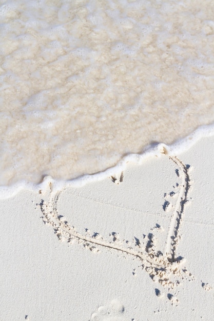 Heart drawing on the beach with wave.