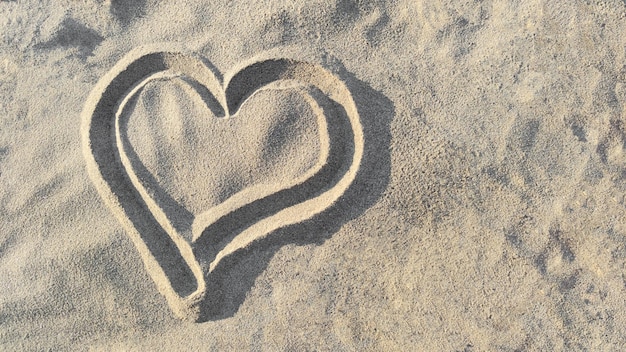 Heart drawn on sand top view, concept of love and health, copy space