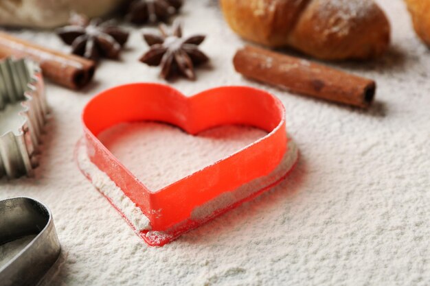 Heart of flour, croissant and spices on gray background