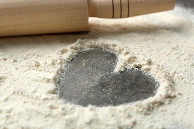 Heart of flour and rolling pin on gray background