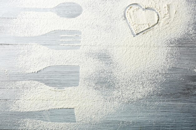 Heart of flour on wooden background