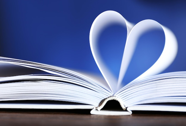 Heart from book pages on blue blurred background