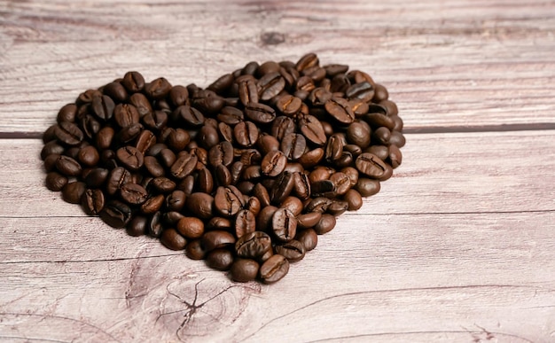 コーヒー豆からのハート木製の背景にローストコーヒー豆のハートセレクティブフォーカス