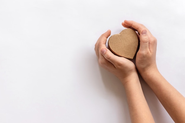 Cuore di carta artigianale nelle mani di un bambino piccolo su uno sfondo bianco. concetto ecologico, ecologico, salva la terra e la giornata mondiale dell'ambiente, l'amore, il giorno di san valentino. copia spazio per il testo, mock up