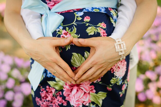 Cuore dalle mani di un marito e una moglie su una pancia incinta