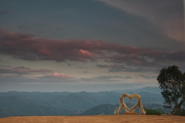 A heart grass arch on a field with mountain range and twilight sky in an evening