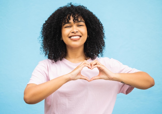 Heart hand sign black woman and smile portrait of a young person showing love gesture African female happiness and excited space with hands making emoji shape with blue studio background isolated