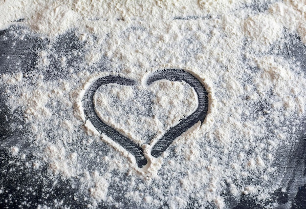 The heart is drawn on flour scattered on a dark table.