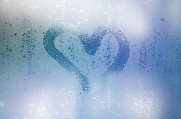 The heart is painted on the misted glass in the winter