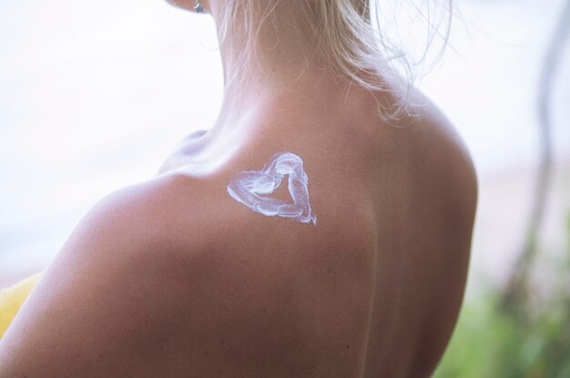 a heart is painted on a woman's shoulder with cream